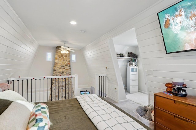 bedroom with ceiling fan, light carpet, and wood walls