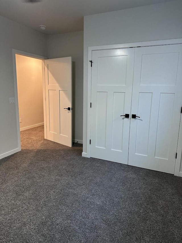 unfurnished bedroom with a closet and dark colored carpet