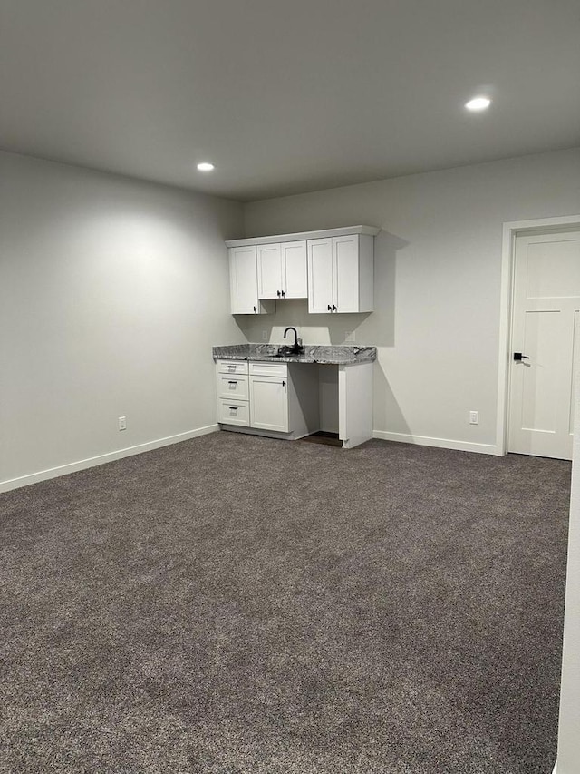 kitchen with dark carpet, sink, and white cabinetry