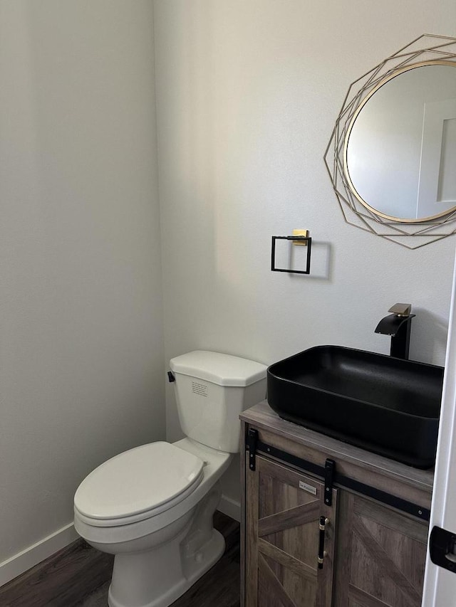 bathroom with wood-type flooring, toilet, and vanity