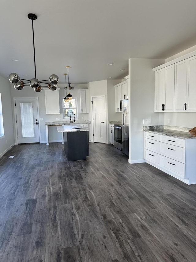 kitchen with hanging light fixtures, white cabinets, appliances with stainless steel finishes, and dark hardwood / wood-style floors