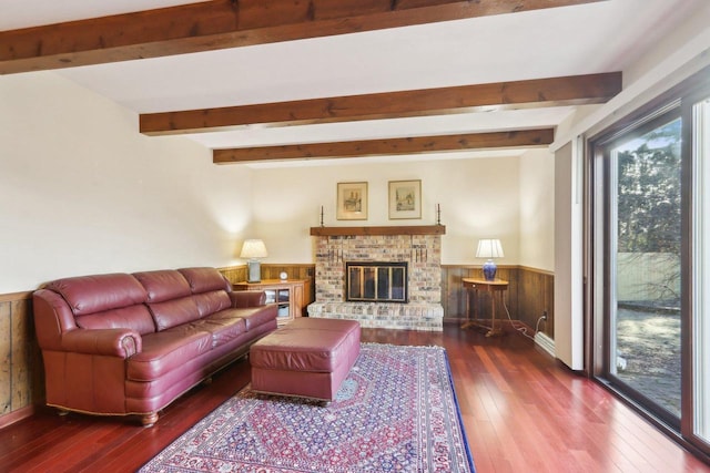 living room featuring beam ceiling, a fireplace, wood-type flooring, and wooden walls