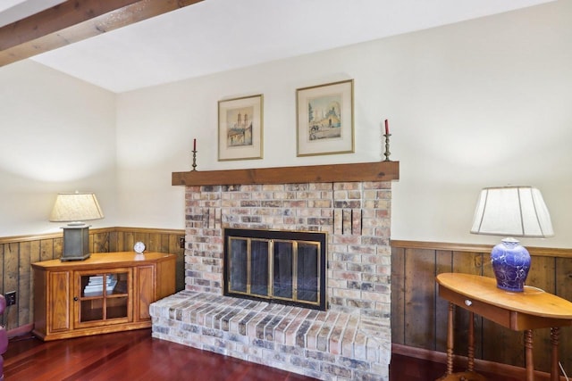 living room featuring a brick fireplace, dark hardwood / wood-style flooring, and wooden walls