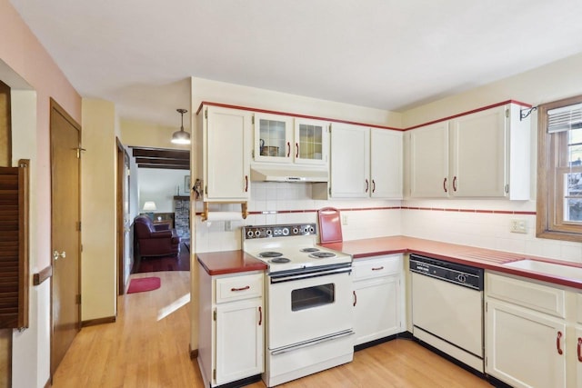 kitchen with white appliances, white cabinetry, decorative backsplash, hanging light fixtures, and light wood-type flooring