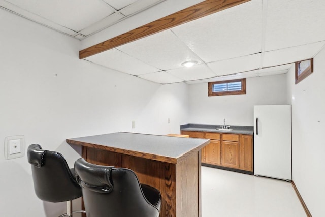 bar with a paneled ceiling, sink, and white refrigerator