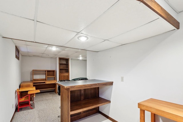 basement with a paneled ceiling and carpet