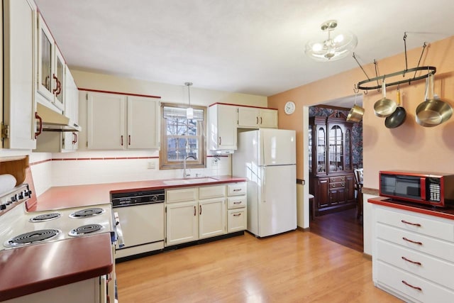 kitchen with white cabinetry, sink, white appliances, and hanging light fixtures