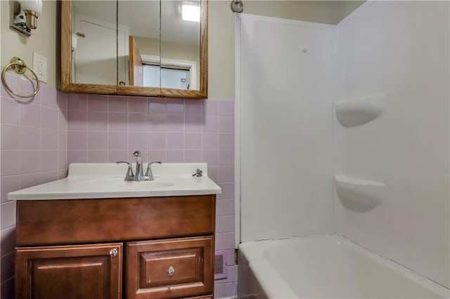 bathroom with vanity, tile walls, and bathing tub / shower combination