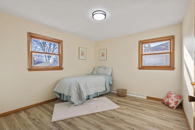 bedroom with baseboard heating and light hardwood / wood-style floors