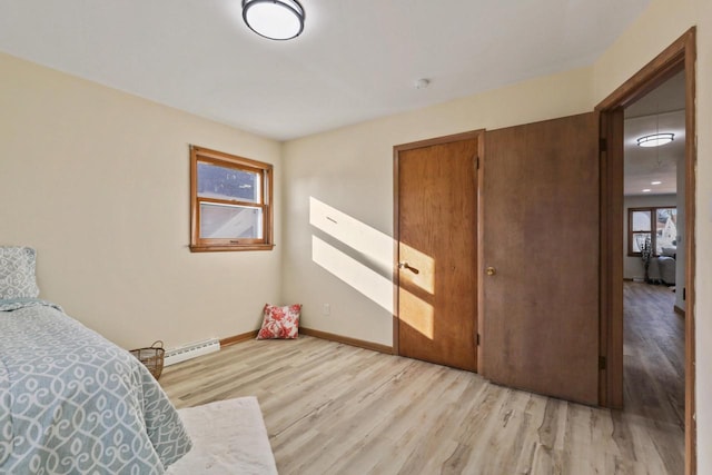 bedroom with a closet, light hardwood / wood-style floors, and a baseboard radiator