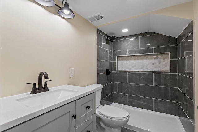 bathroom with toilet, vanity, and tiled shower