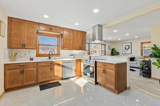 kitchen with kitchen peninsula, island exhaust hood, stainless steel appliances, backsplash, and sink