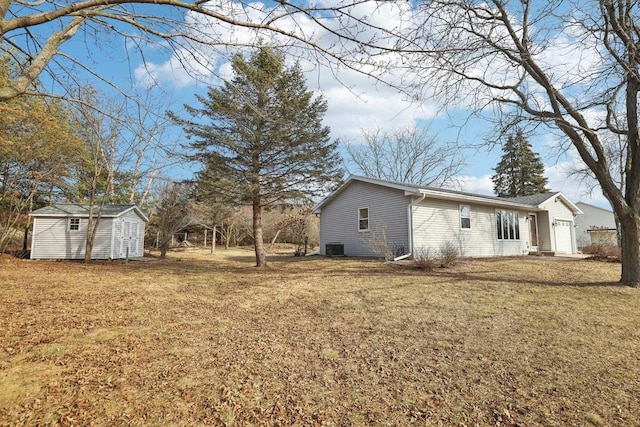 view of side of property featuring a yard, central air condition unit, and a storage unit