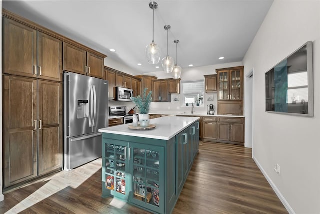 kitchen featuring decorative light fixtures, dark hardwood / wood-style floors, a kitchen island, sink, and stainless steel appliances