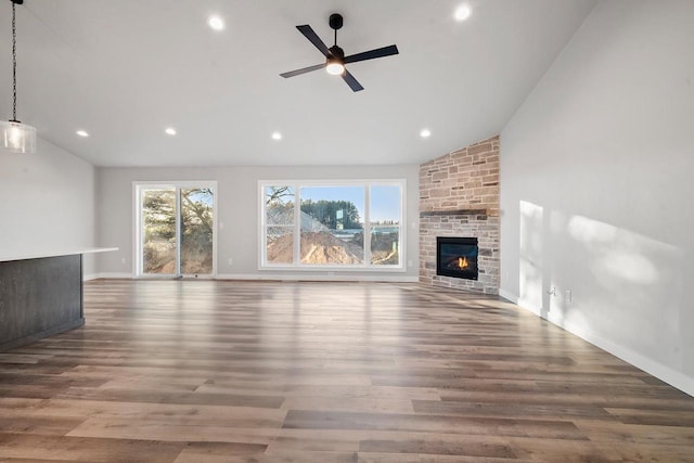 unfurnished living room featuring plenty of natural light, hardwood / wood-style floors, and a stone fireplace