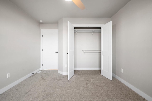 unfurnished bedroom featuring ceiling fan, a closet, and light colored carpet