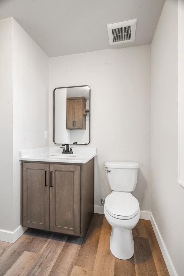 bathroom with toilet, hardwood / wood-style flooring, and vanity
