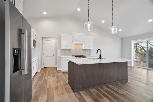 kitchen featuring white cabinets, tasteful backsplash, a kitchen island with sink, vaulted ceiling, and high end refrigerator