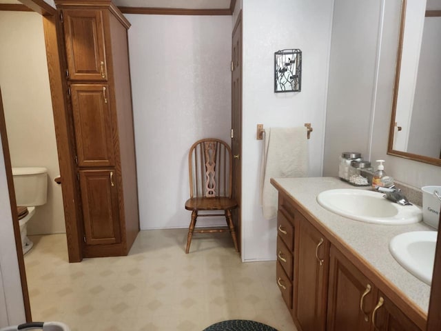 bathroom featuring toilet, vanity, and ornamental molding