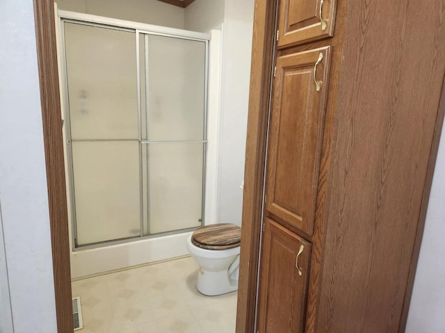 bathroom with toilet and a shower with door