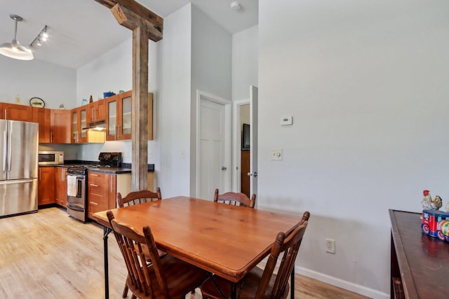 dining area featuring a towering ceiling and light wood-type flooring