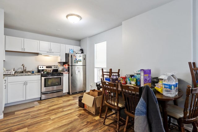 kitchen with white cabinets, light wood-type flooring, appliances with stainless steel finishes, and sink