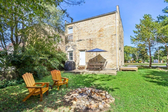 back of property with a yard, a patio area, and a fire pit