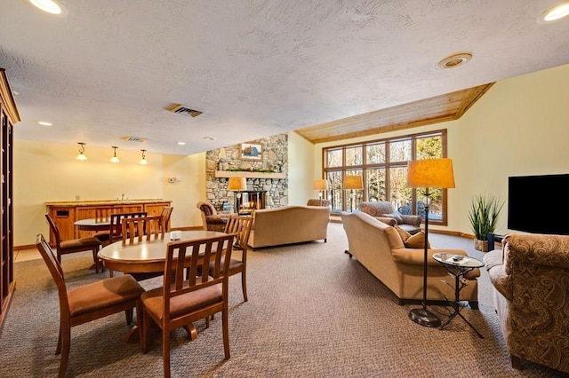 dining room featuring a textured ceiling, carpet flooring, and a fireplace