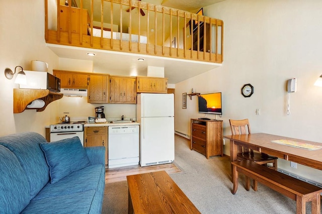 kitchen with a high ceiling, a baseboard radiator, white appliances, and sink