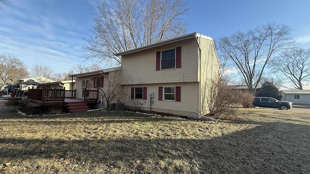 rear view of property with a lawn, central AC unit, and a wooden deck