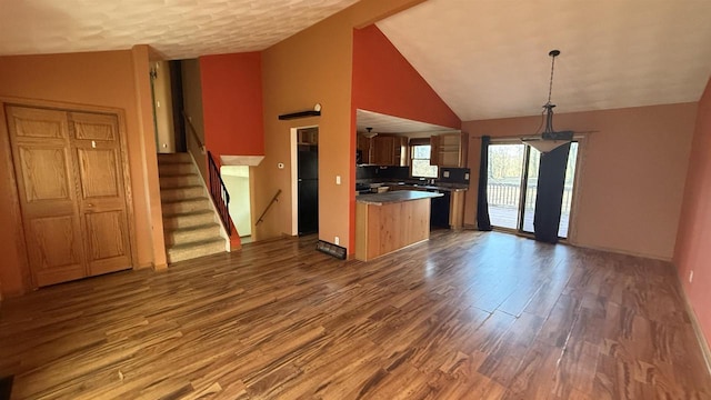 kitchen with decorative light fixtures, hardwood / wood-style floors, decorative backsplash, and high vaulted ceiling