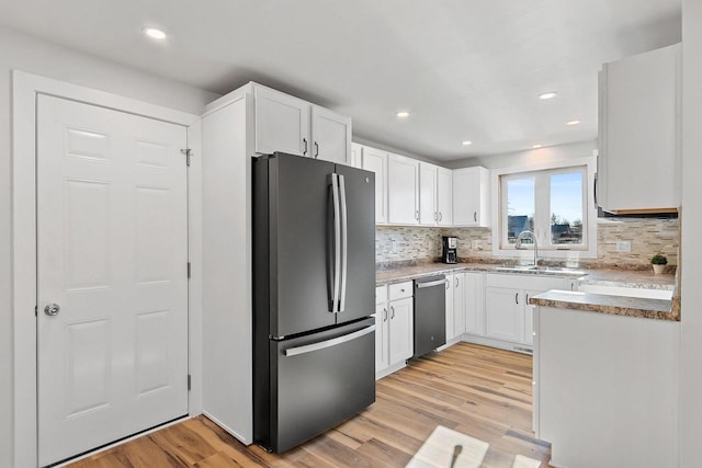 kitchen with white cabinets, appliances with stainless steel finishes, sink, backsplash, and light wood-type flooring