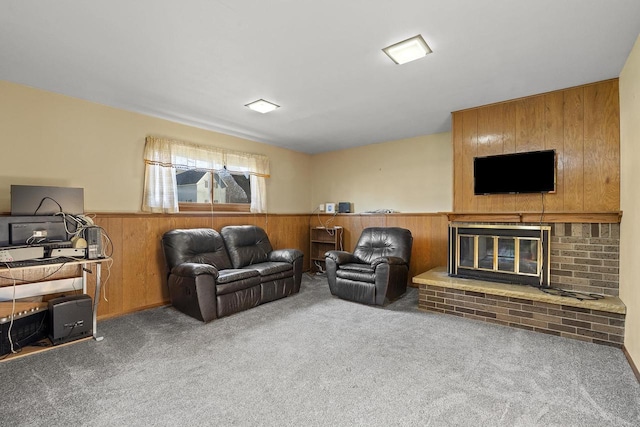 carpeted living room with a brick fireplace and wood walls