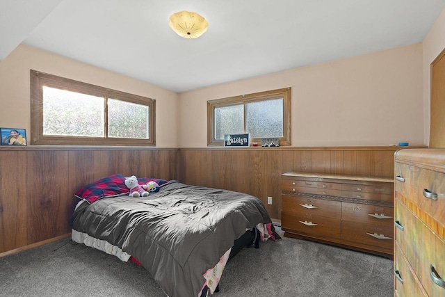 bedroom with light colored carpet and wood walls