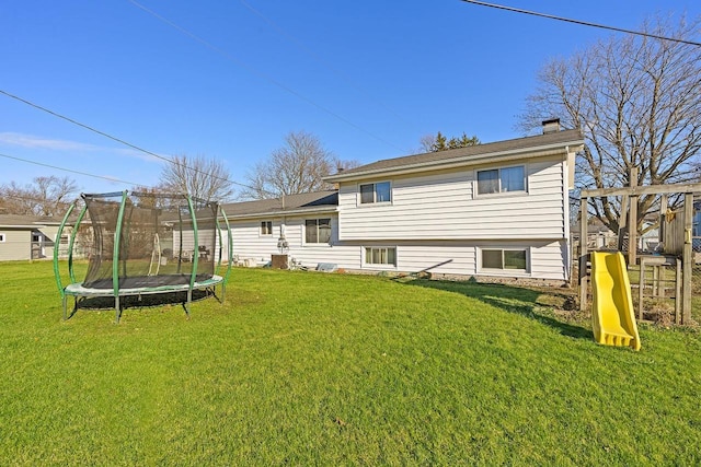 back of property featuring a playground, a trampoline, and a lawn