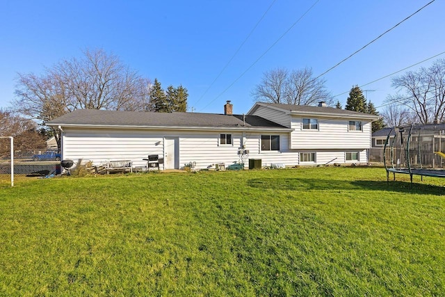 back of property featuring a yard and a trampoline