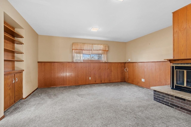 unfurnished living room featuring light carpet, wood walls, and a brick fireplace