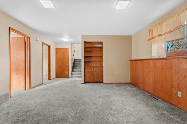 unfurnished room featuring light colored carpet and built in shelves