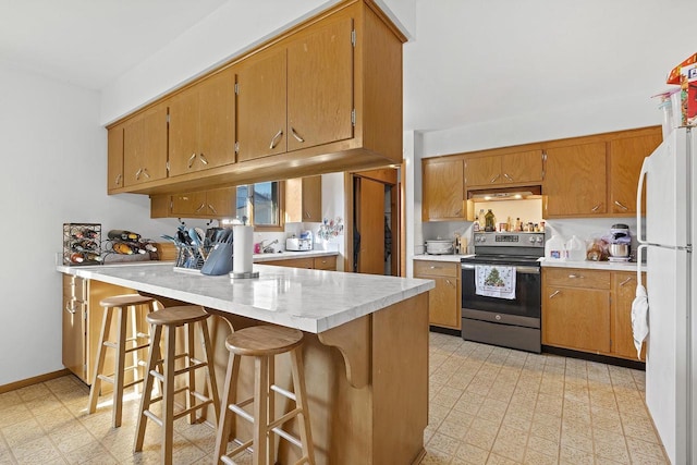 kitchen featuring a kitchen bar, white refrigerator, kitchen peninsula, and stainless steel electric range