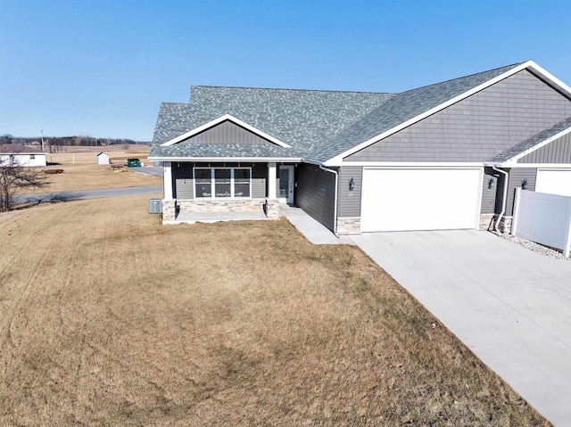 view of front of home with a garage, a front yard, central AC unit, and covered porch