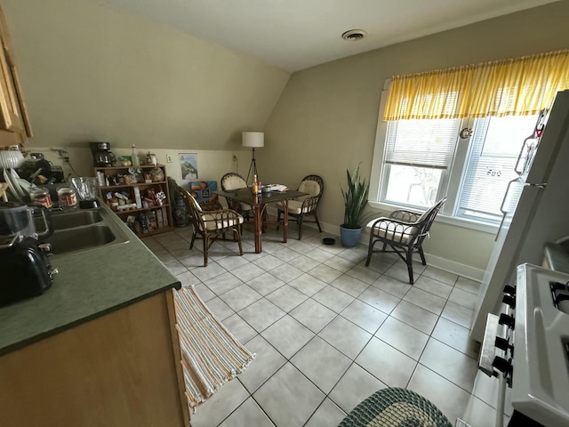 kitchen featuring sink, vaulted ceiling, gas stove, and light tile patterned floors