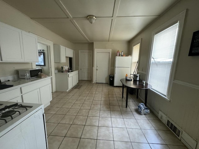 kitchen featuring white appliances, white cabinetry, and light tile patterned floors