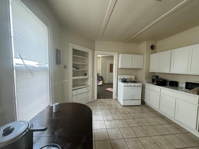 kitchen featuring light tile patterned floors, white cabinetry, white range with gas cooktop, and built in features