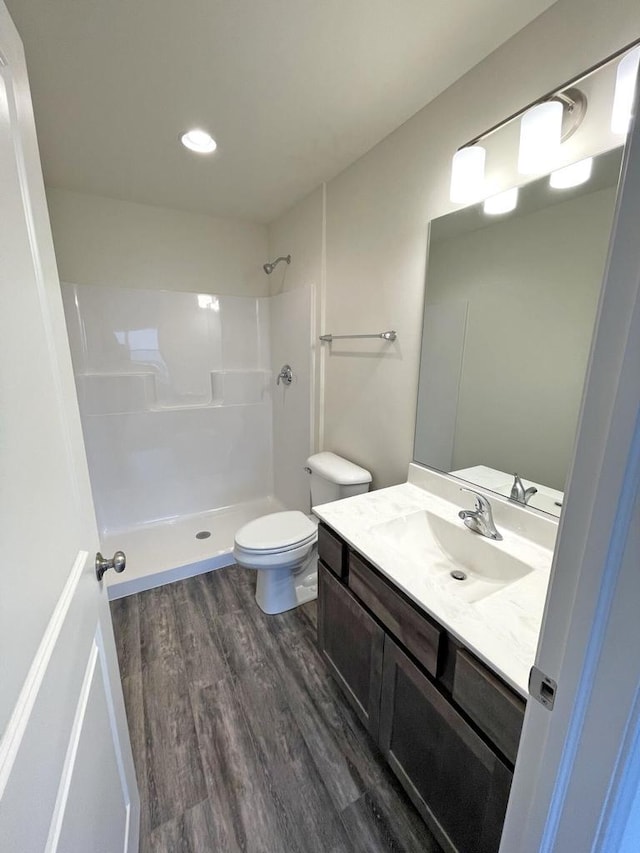 bathroom featuring a shower, wood-type flooring, toilet, and vanity