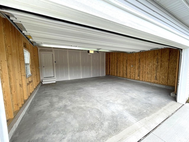 garage featuring a garage door opener and wood walls