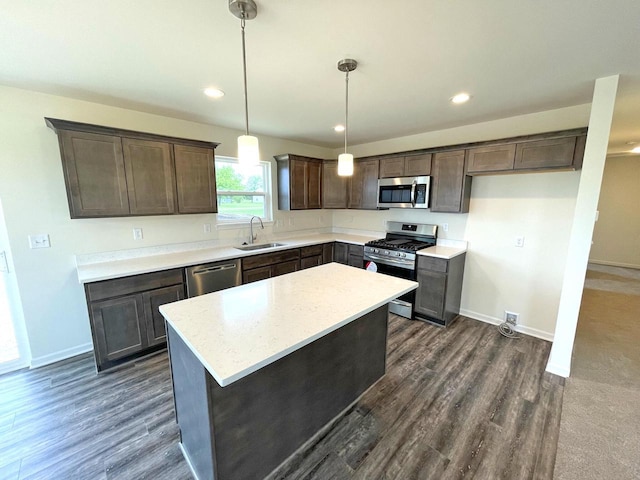 kitchen featuring pendant lighting, appliances with stainless steel finishes, a center island, dark wood-type flooring, and sink