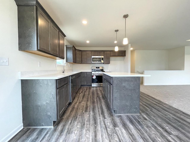 kitchen featuring a center island, appliances with stainless steel finishes, sink, pendant lighting, and dark wood-type flooring