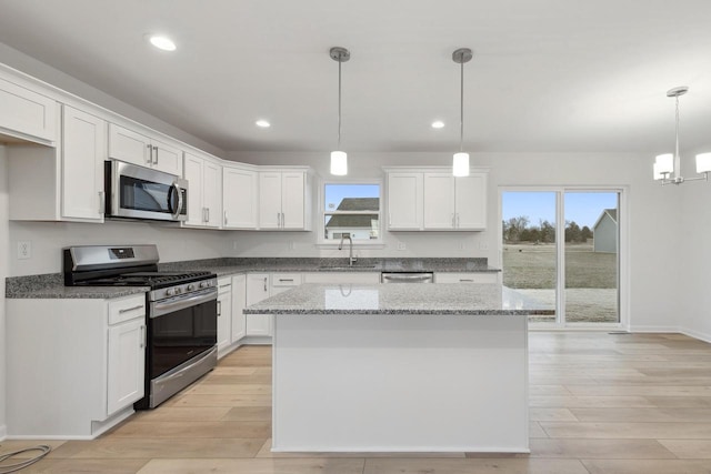 kitchen with white cabinets, decorative light fixtures, appliances with stainless steel finishes, and sink