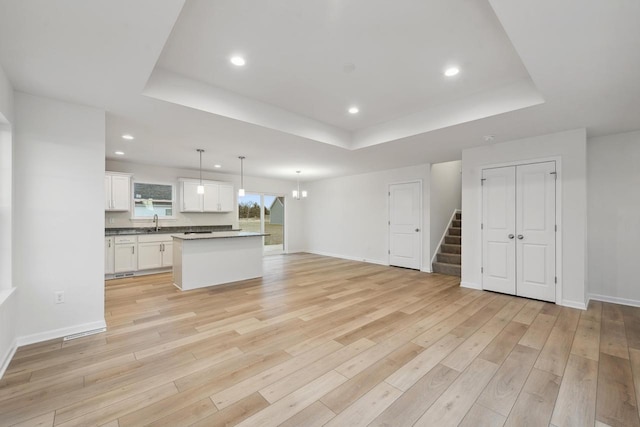 kitchen featuring white cabinetry, a tray ceiling, a center island, and hanging light fixtures