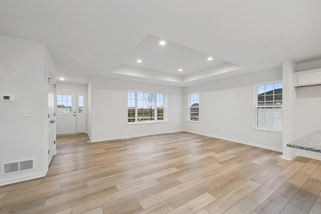 unfurnished living room with a raised ceiling and light hardwood / wood-style floors